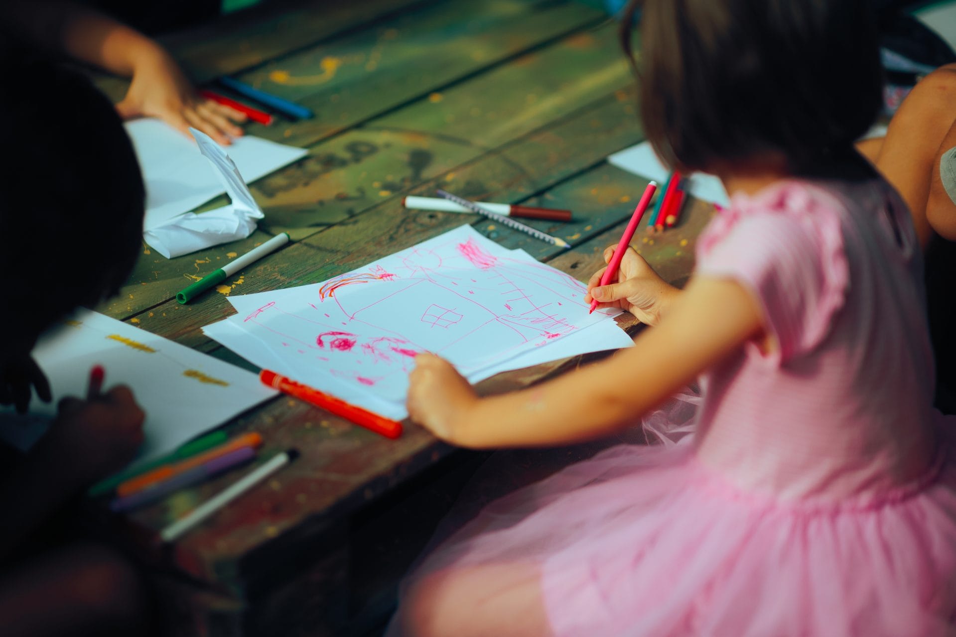 Two young children coloring with crayons and markers.