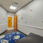 Hallway view with foam floor tiles leading to therapy rooms and open play area.