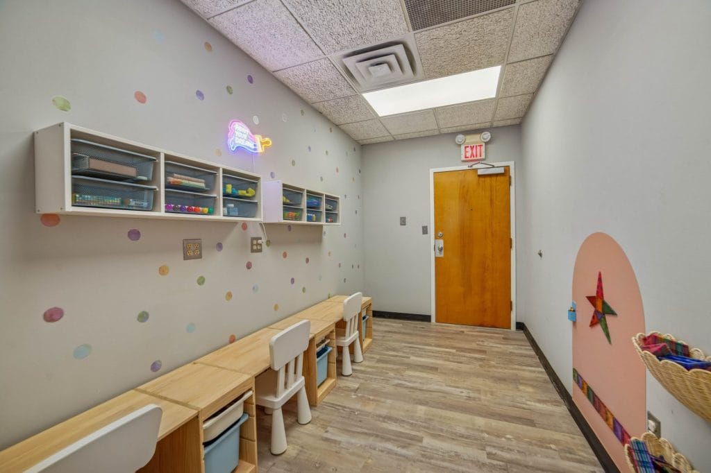 Corridor with bench seating, wall art, and doorway leading to therapy rooms.