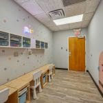 Corridor with bench seating, wall art, and doorway leading to therapy rooms.