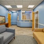 Alternate view of the waiting area showing cushioned chairs, framed artwork, and hallway toward exam rooms.
